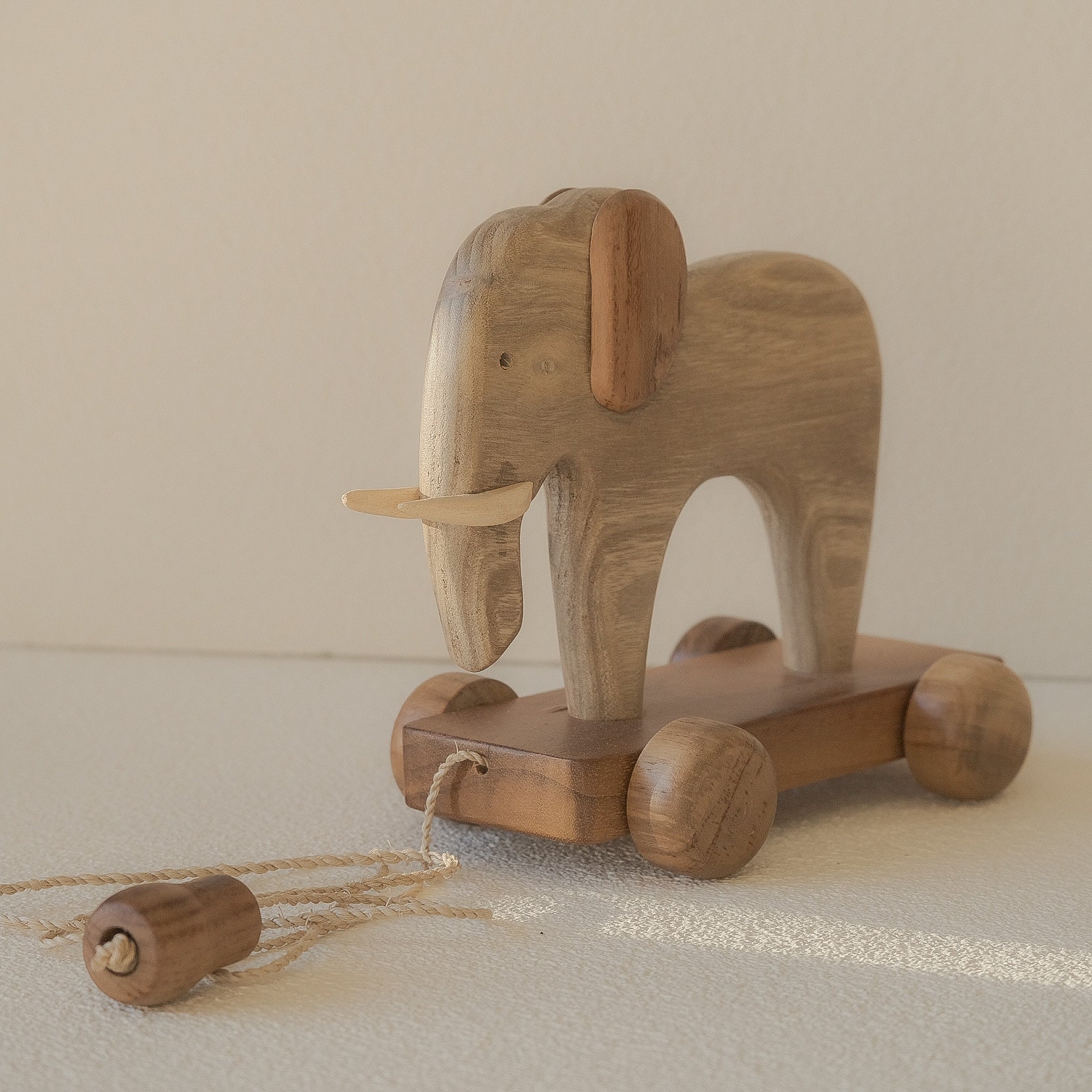 Wooden elephant toy with wheels on a neutral background