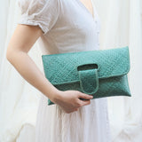 Person holding a green clutch against a white background
