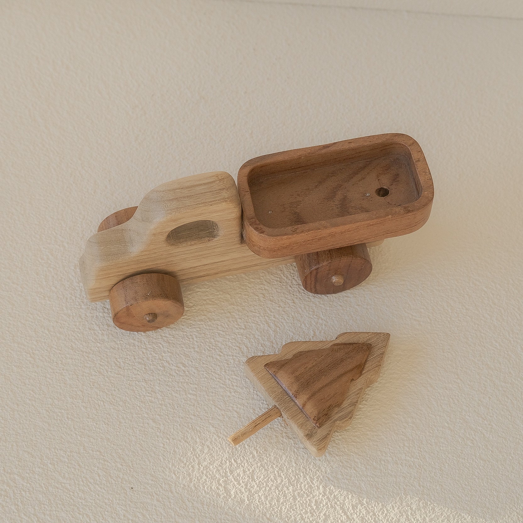 Wooden toy car and truck on a beige surface
