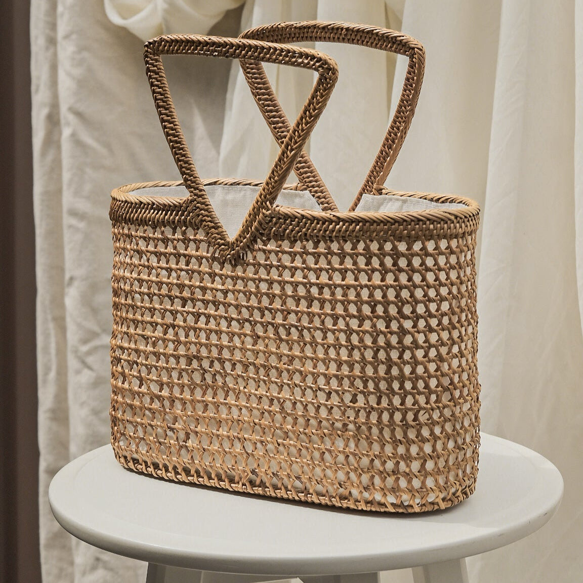 Woven straw bag on a white stool with a neutral background