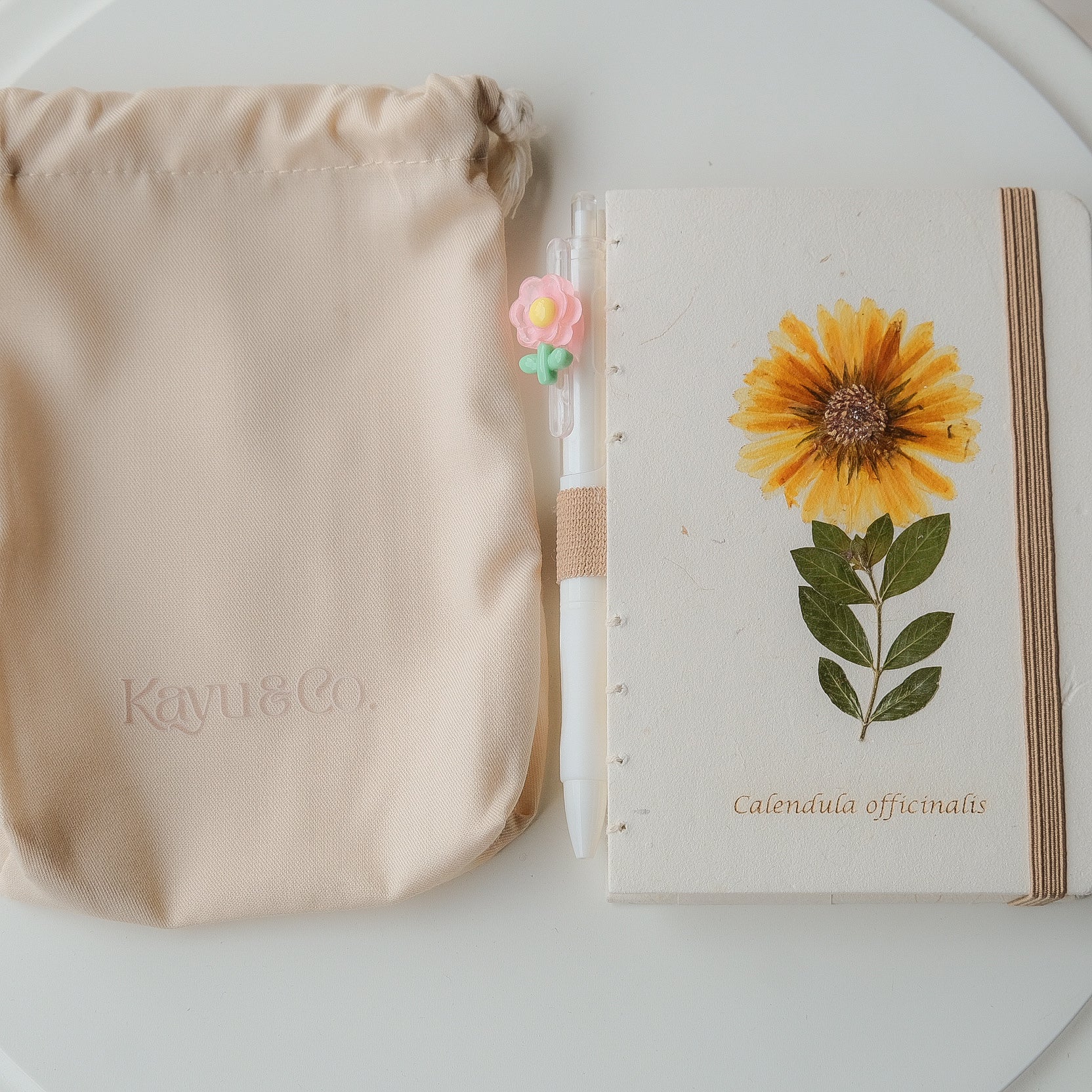 A6 recycled paper journal with real pressed calendula flower on the cover, paired with a floral pen and soft pouch