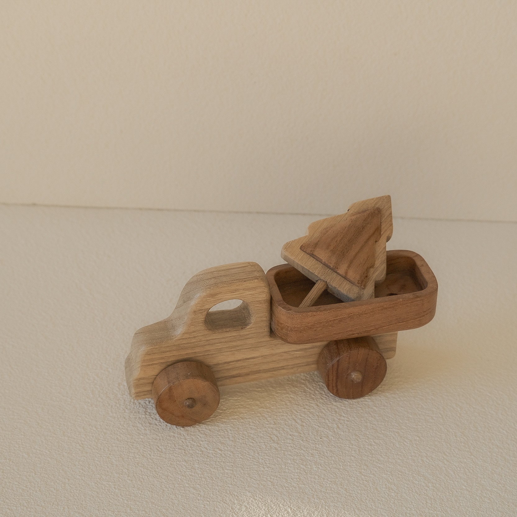 Wooden toy truck with an open bed on a beige surface