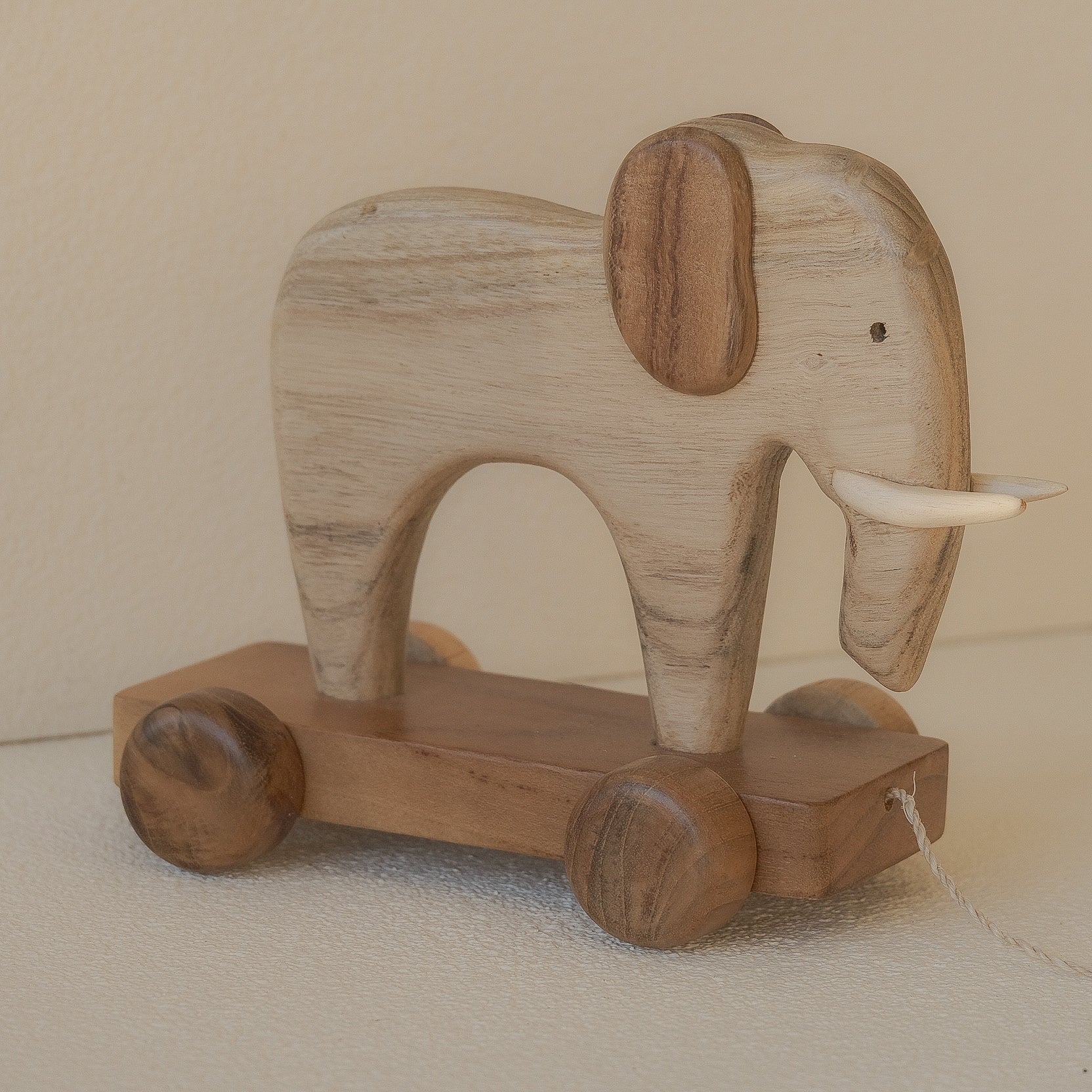 Wooden elephant toy on wheels with a plain background