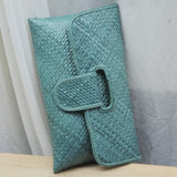 Teal clutch bag on a light wooden surface