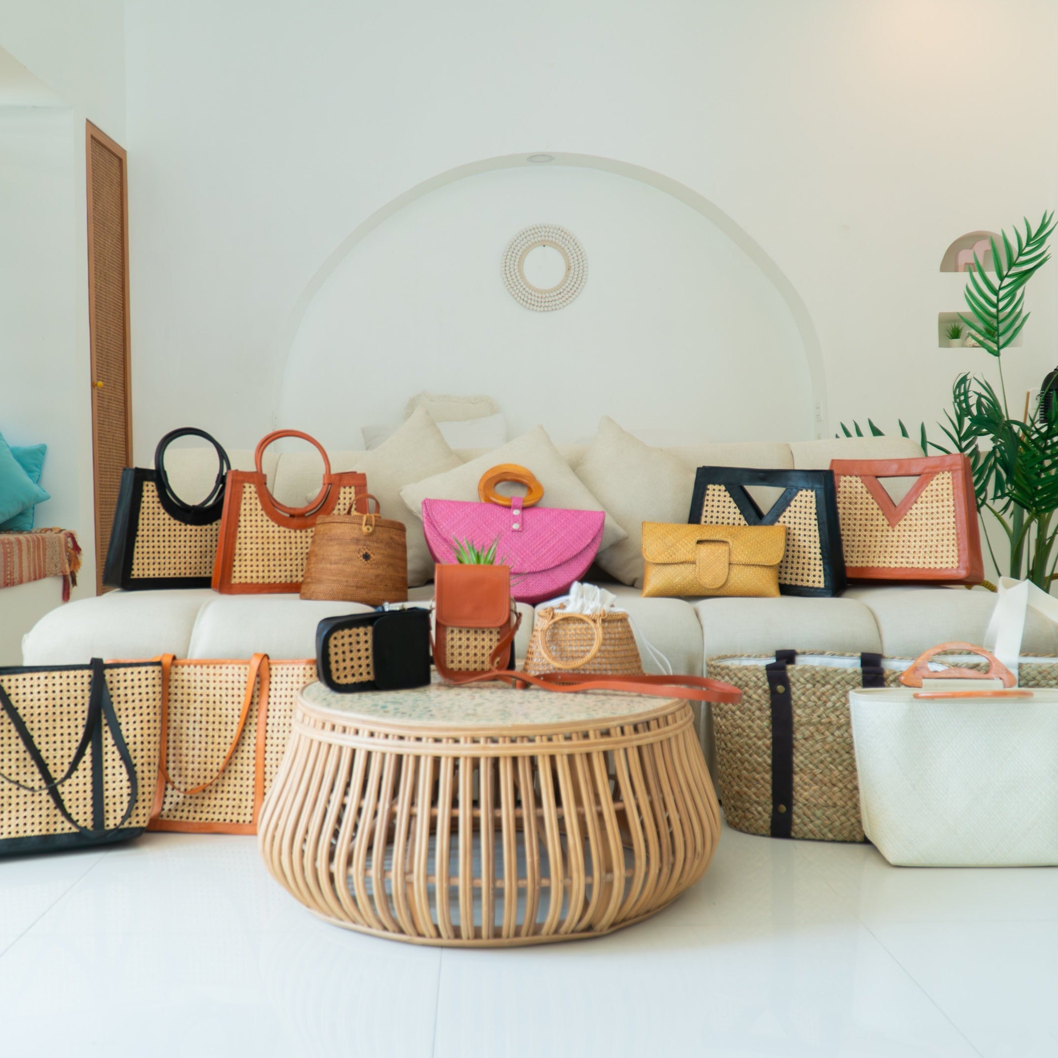 Collection of handbags and baskets displayed in a room with a white sofa and wooden floor.