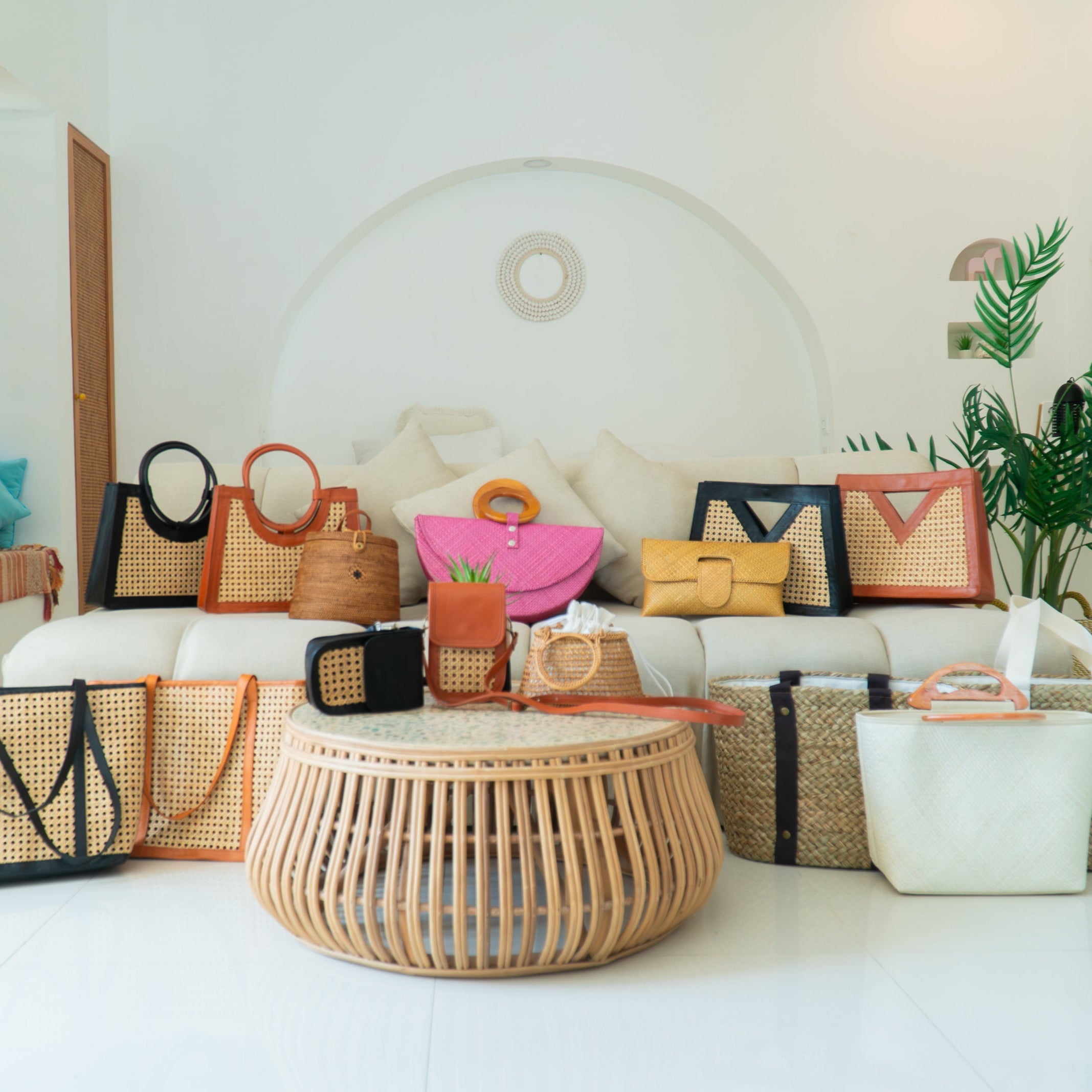 Collection of handbags and baskets displayed in a room with a white sofa and tiles floor.