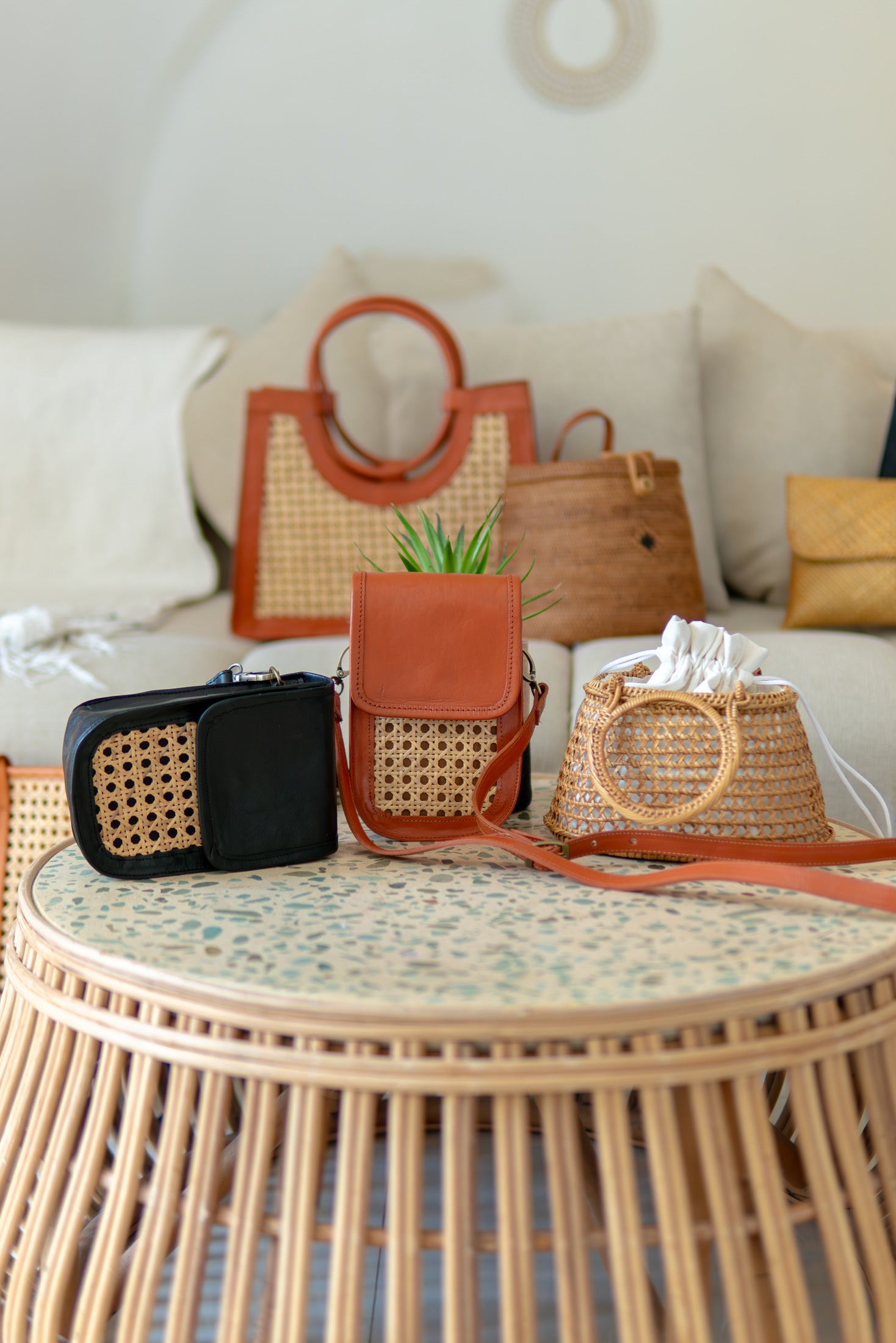Collection of handbags on a round wicker table with a neutral background
