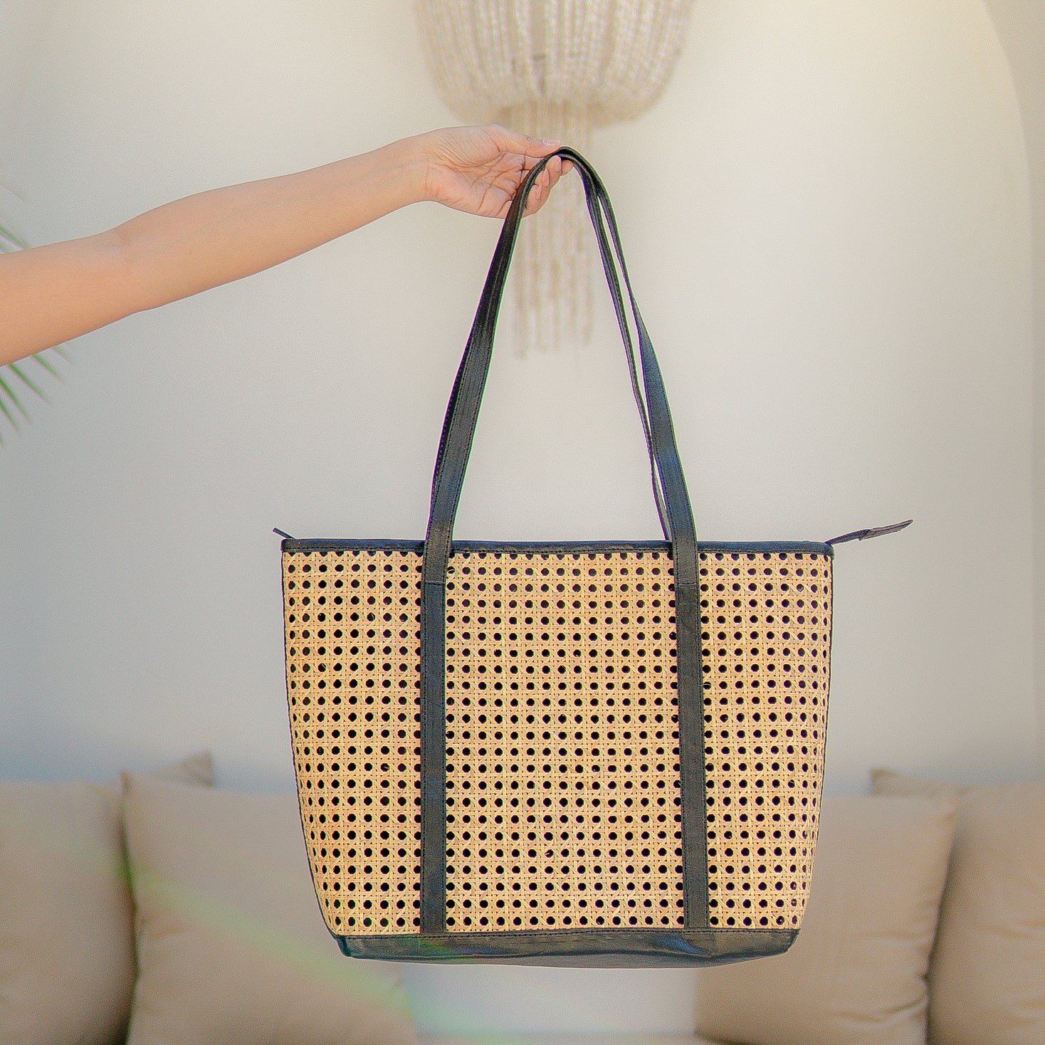 Sol tote bag with black straps held by a person against a neutral background