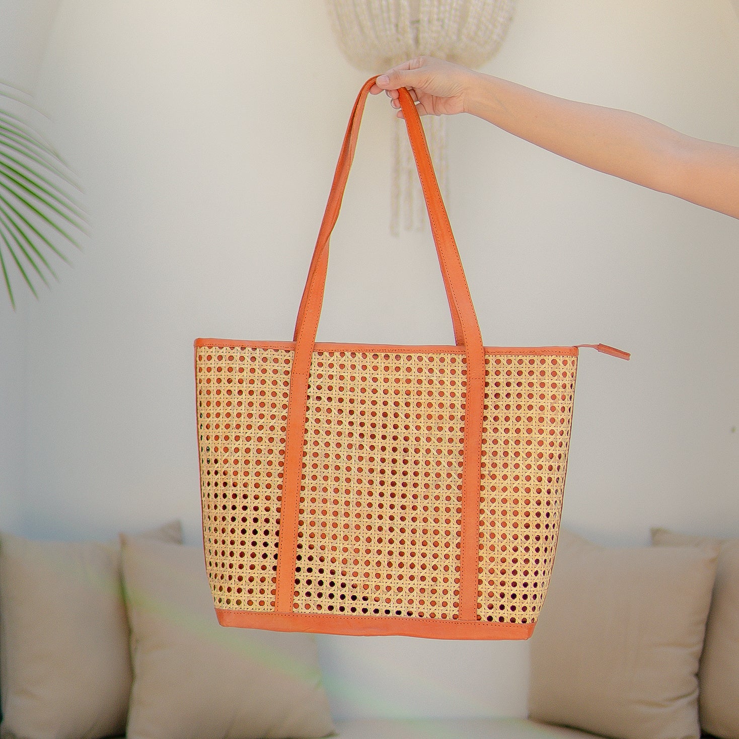 Sunset Sol tote bag with orange trim held by a hand against a neutral background