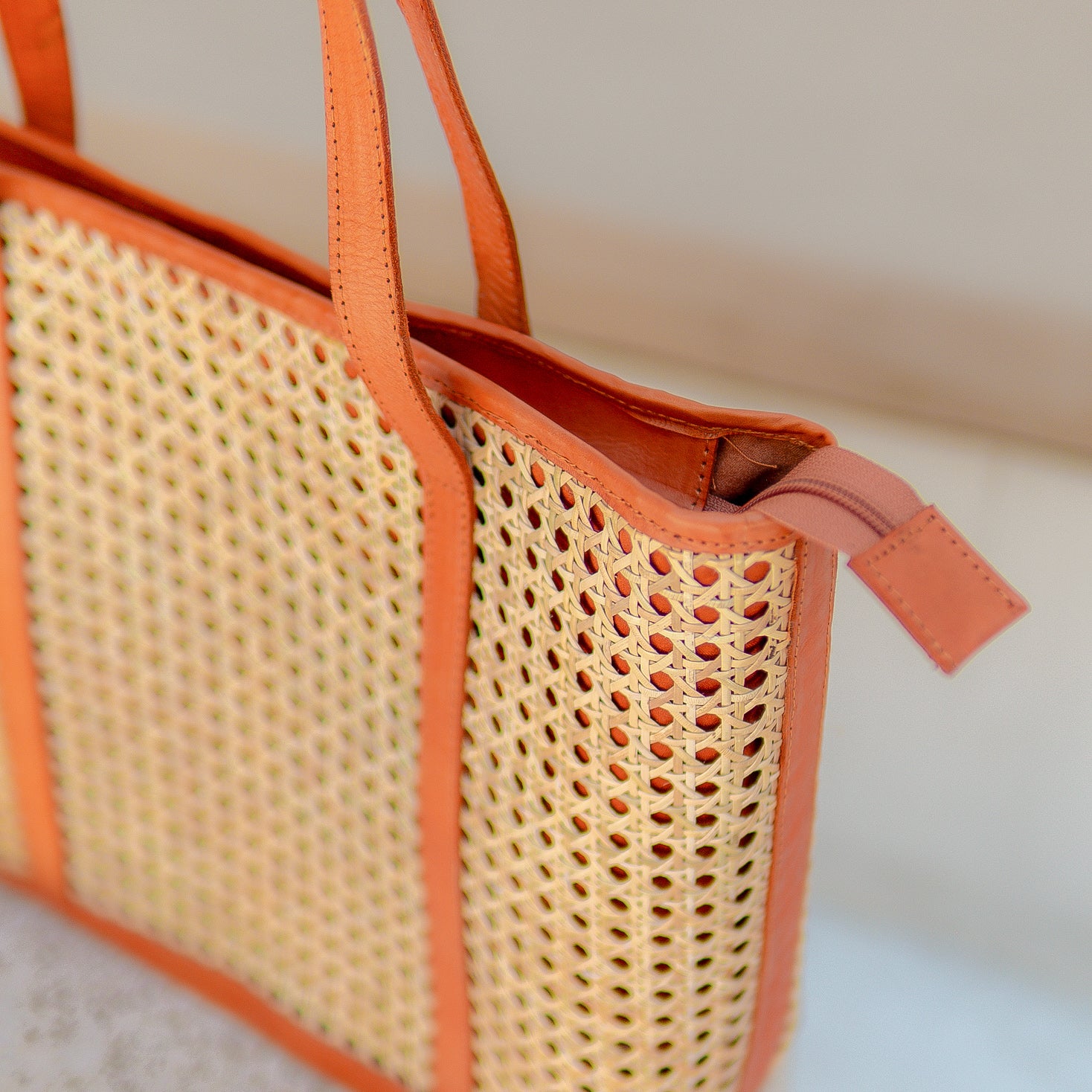 Sunset Sol rattan bag with orange accents on a neutral background