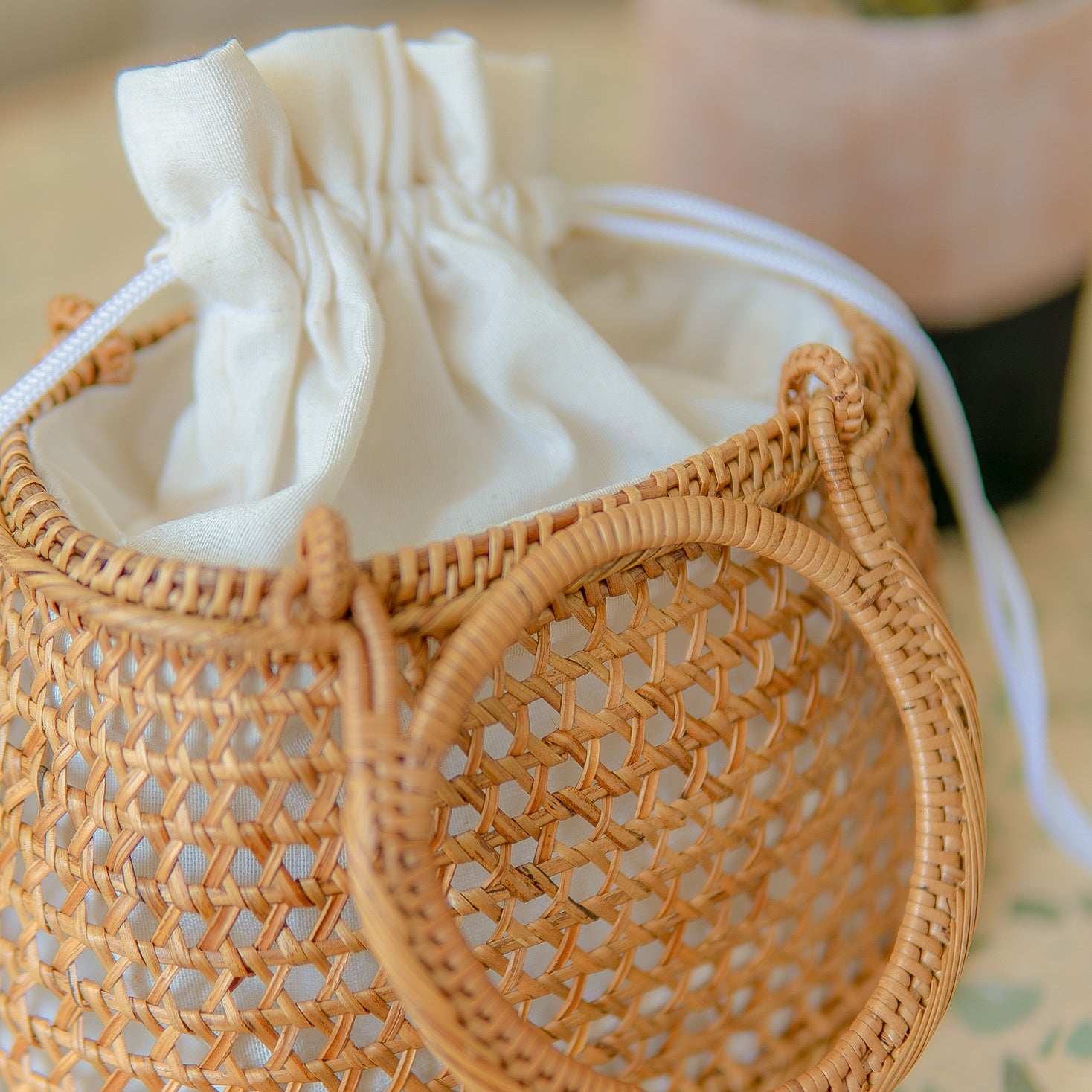 Camilla circle bag with a drawstring bag inside on a blurred background
