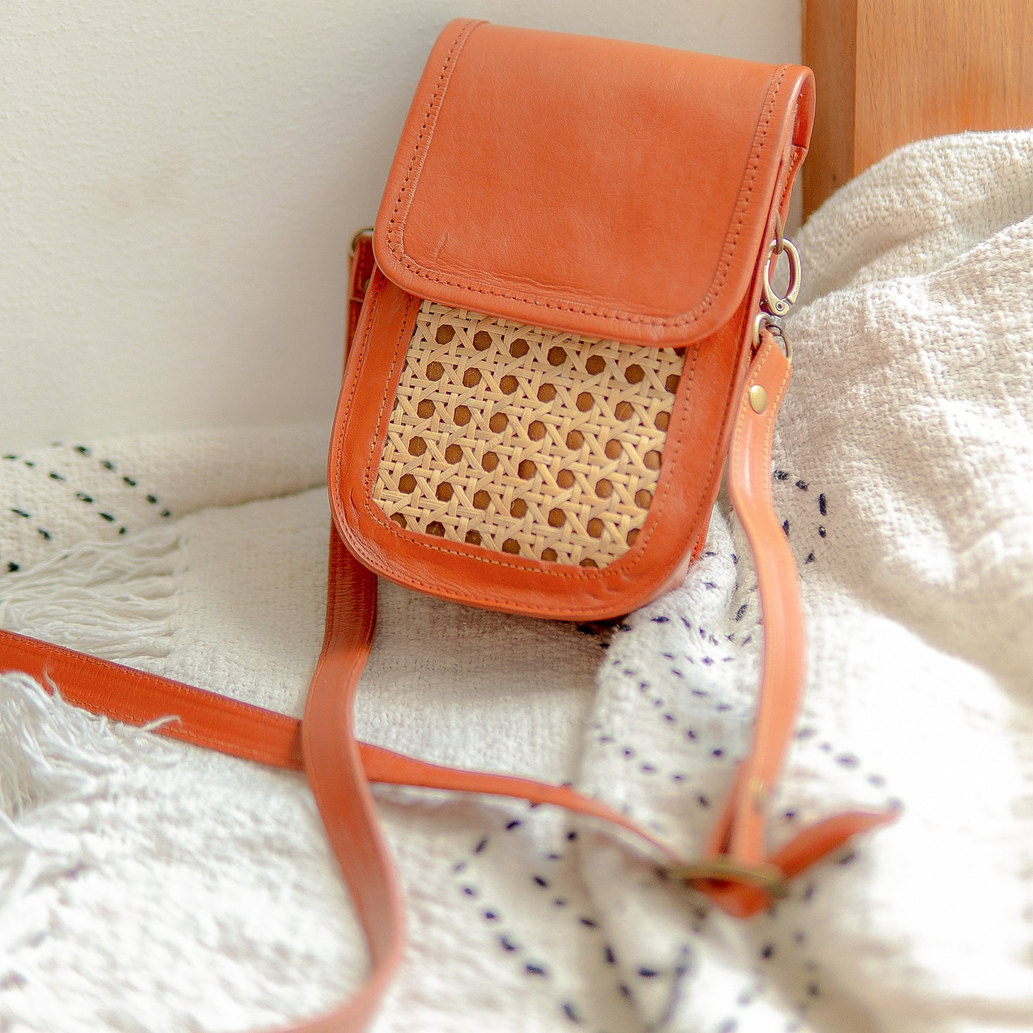 Orange crossbody bag with woven detail on a textured surface
