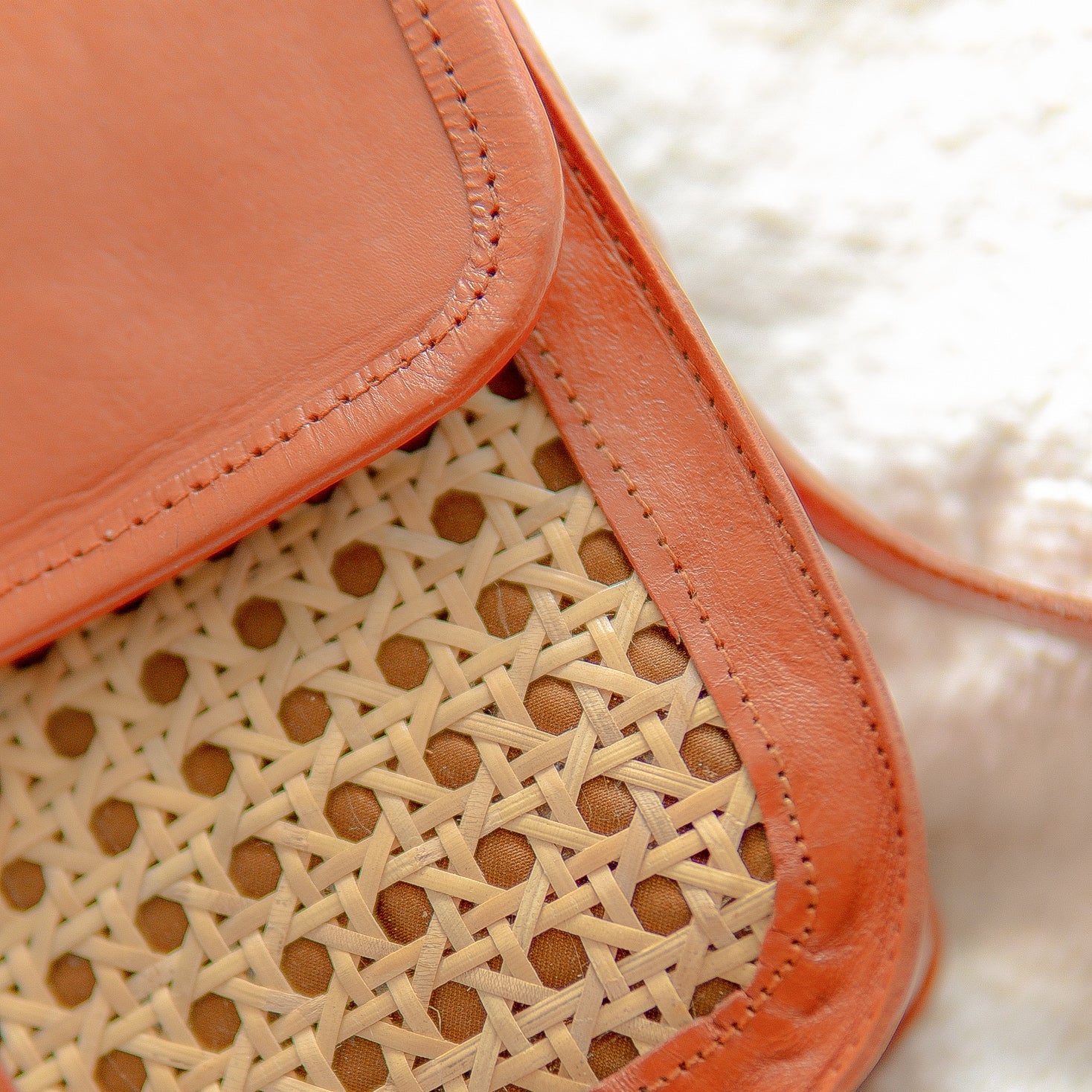 Close-up of a handbag with a woven pattern and coral-colored flap.