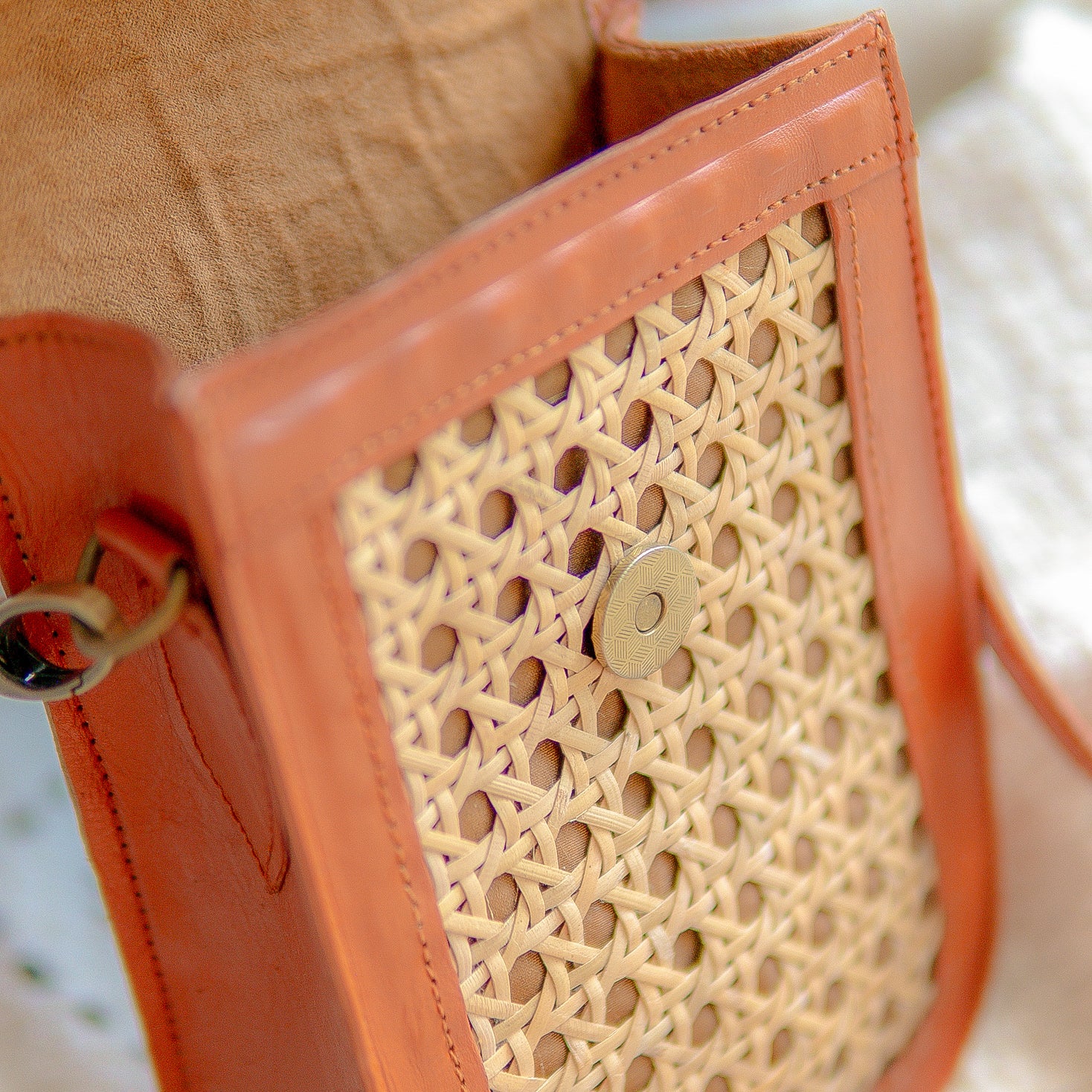 Close-up of a brown handbag with sued inner fabric and a textured pattern. Warm tan Harper phone bag on woven textile