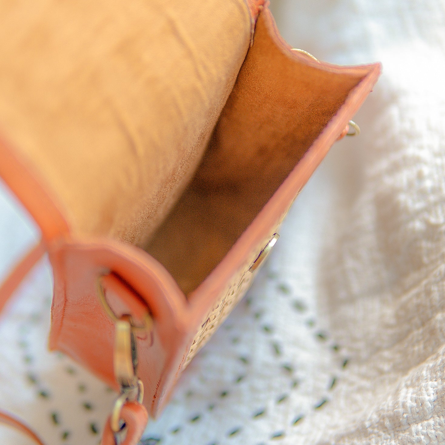 Close-up of a peach-colored handbag with sued fabric on a textured white surface