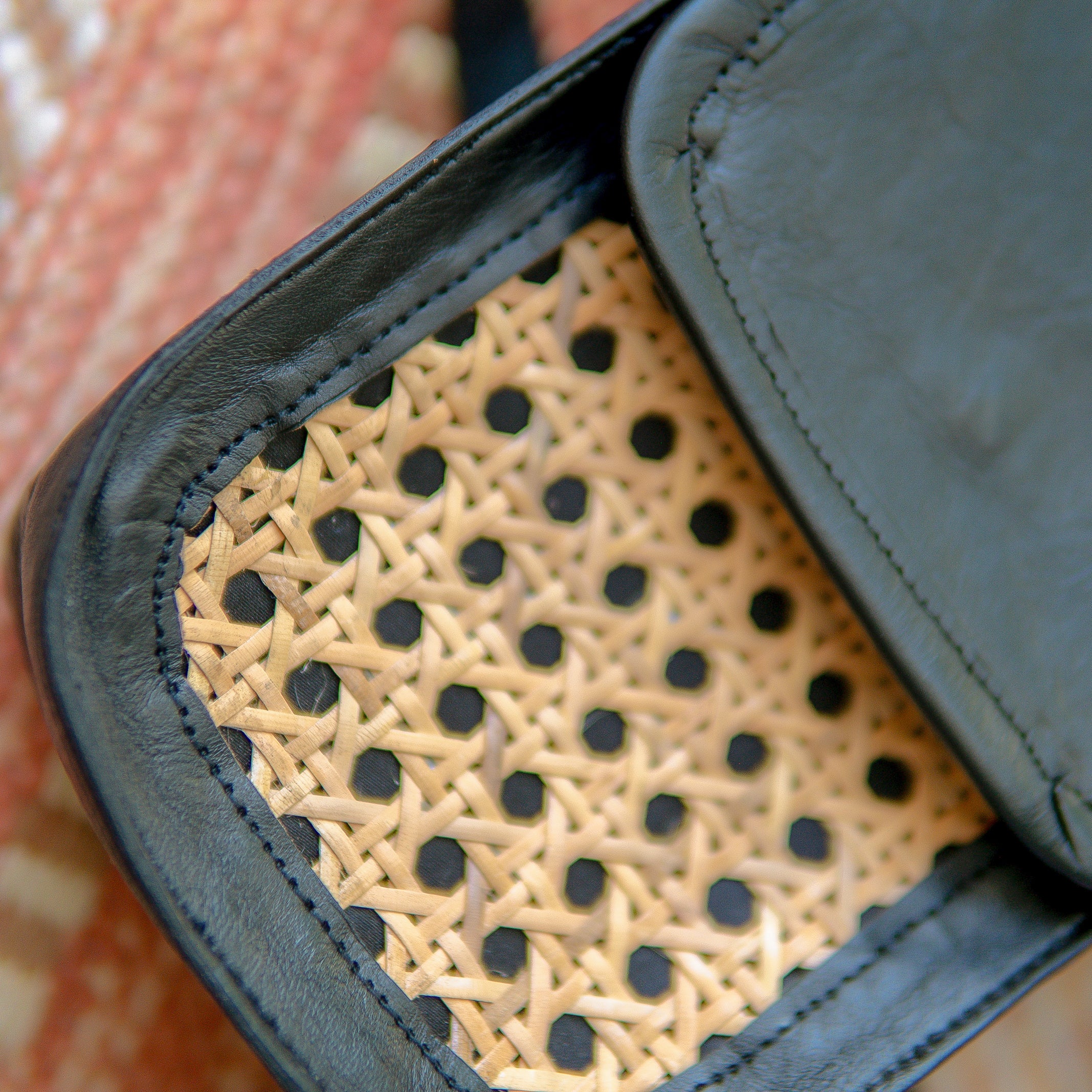 Close-up of Harper Sling Bag with black leather and woven rattan pattern