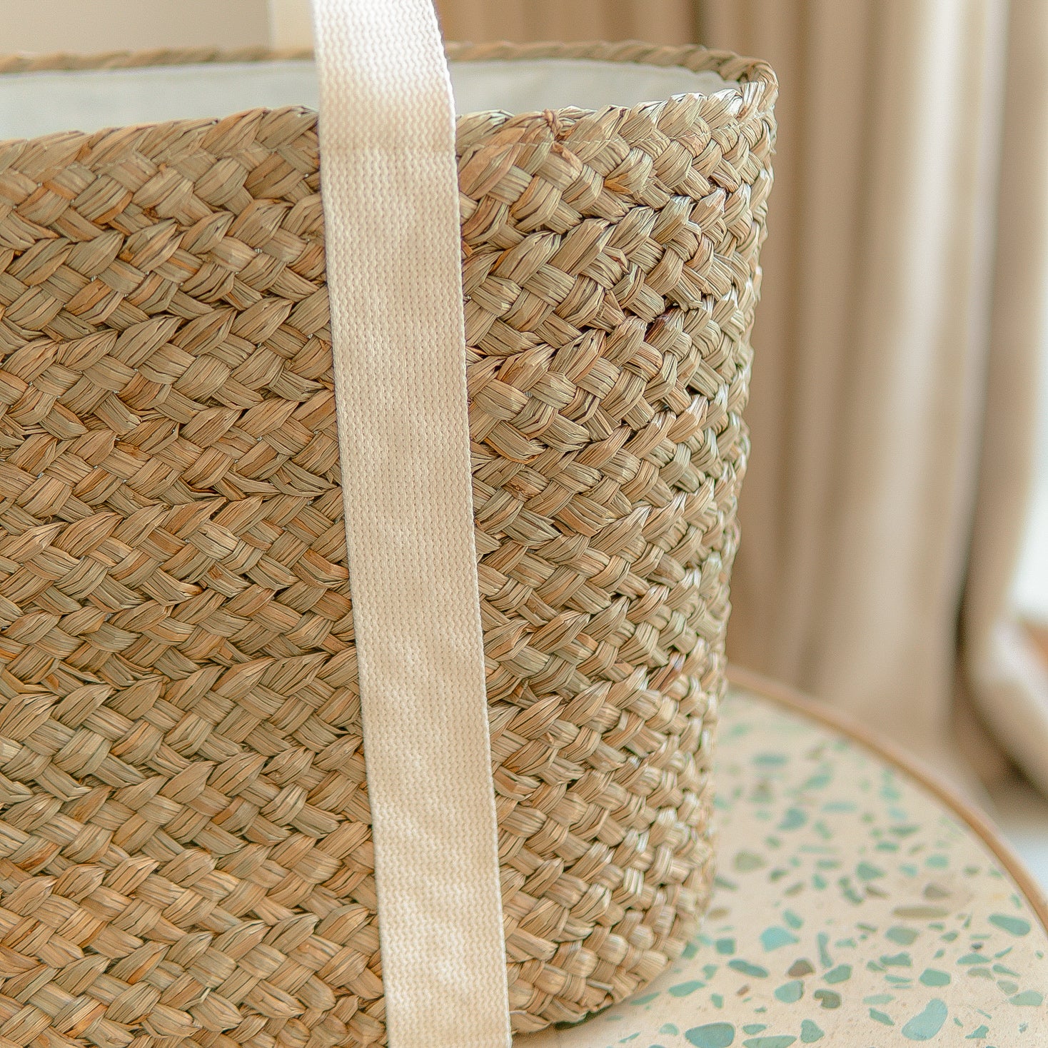 Woven basket with a handle on a surface with a neutral background