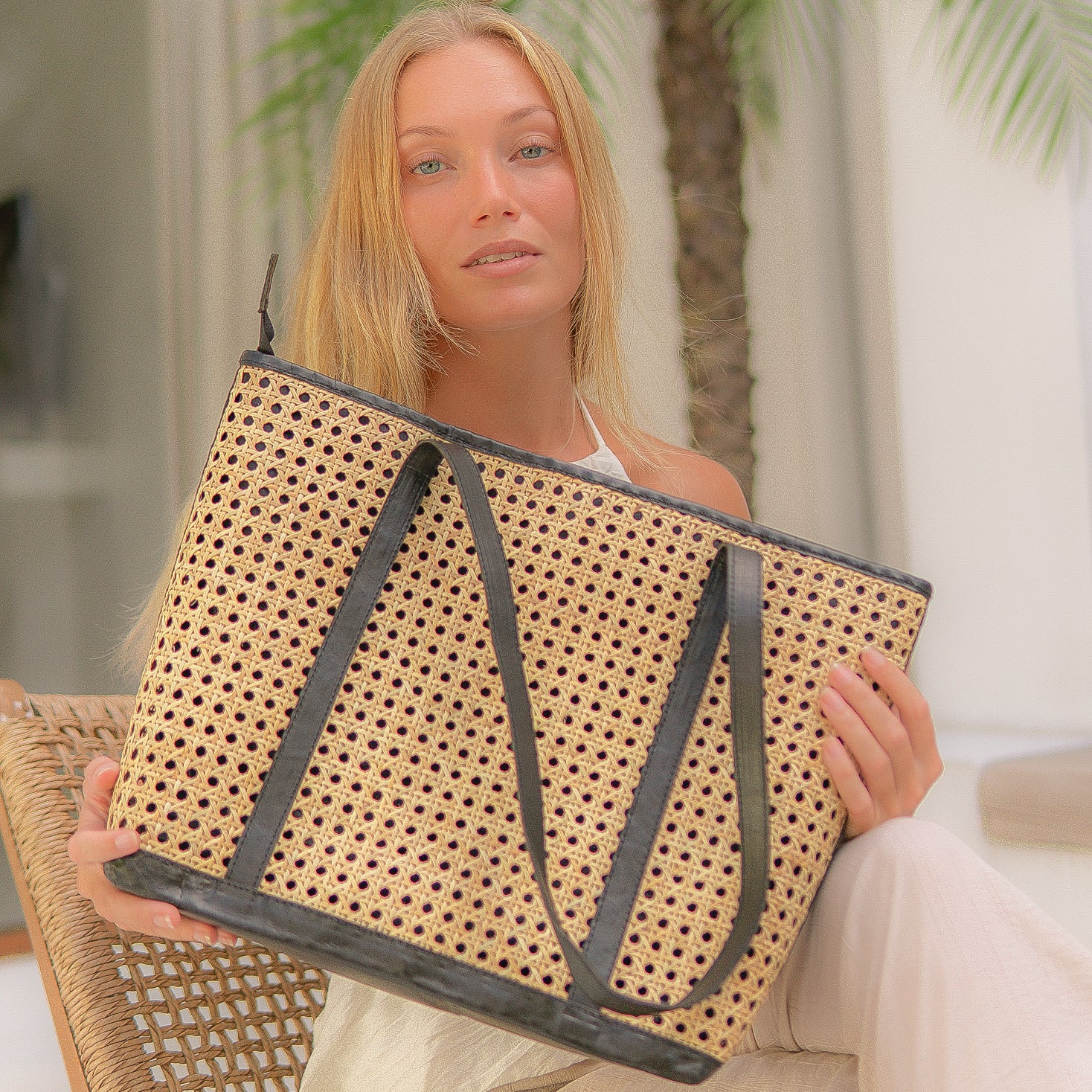Woman holding a woven handbag with a blurred indoor background