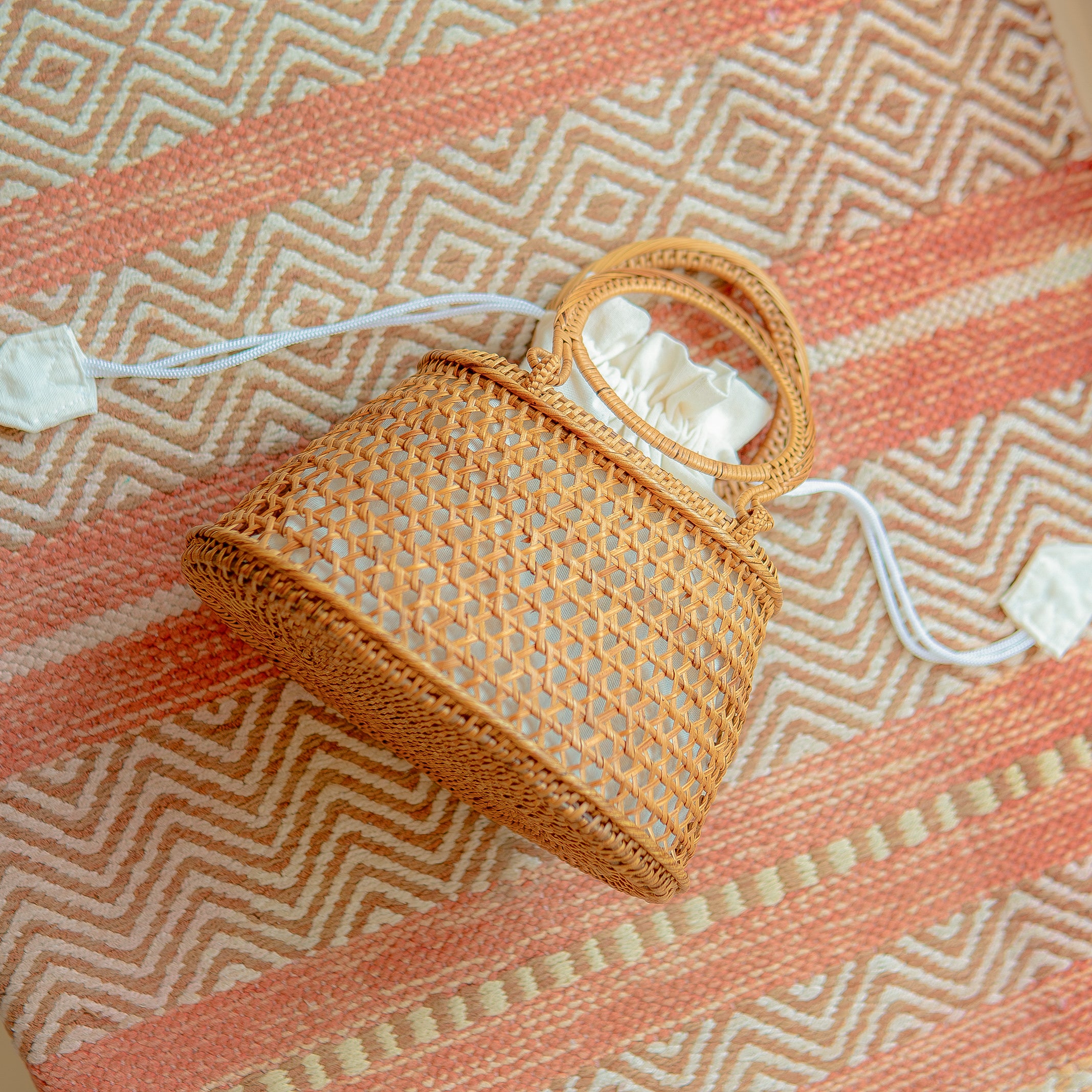 Camilla circle bag with a handle on a patterned fabric background