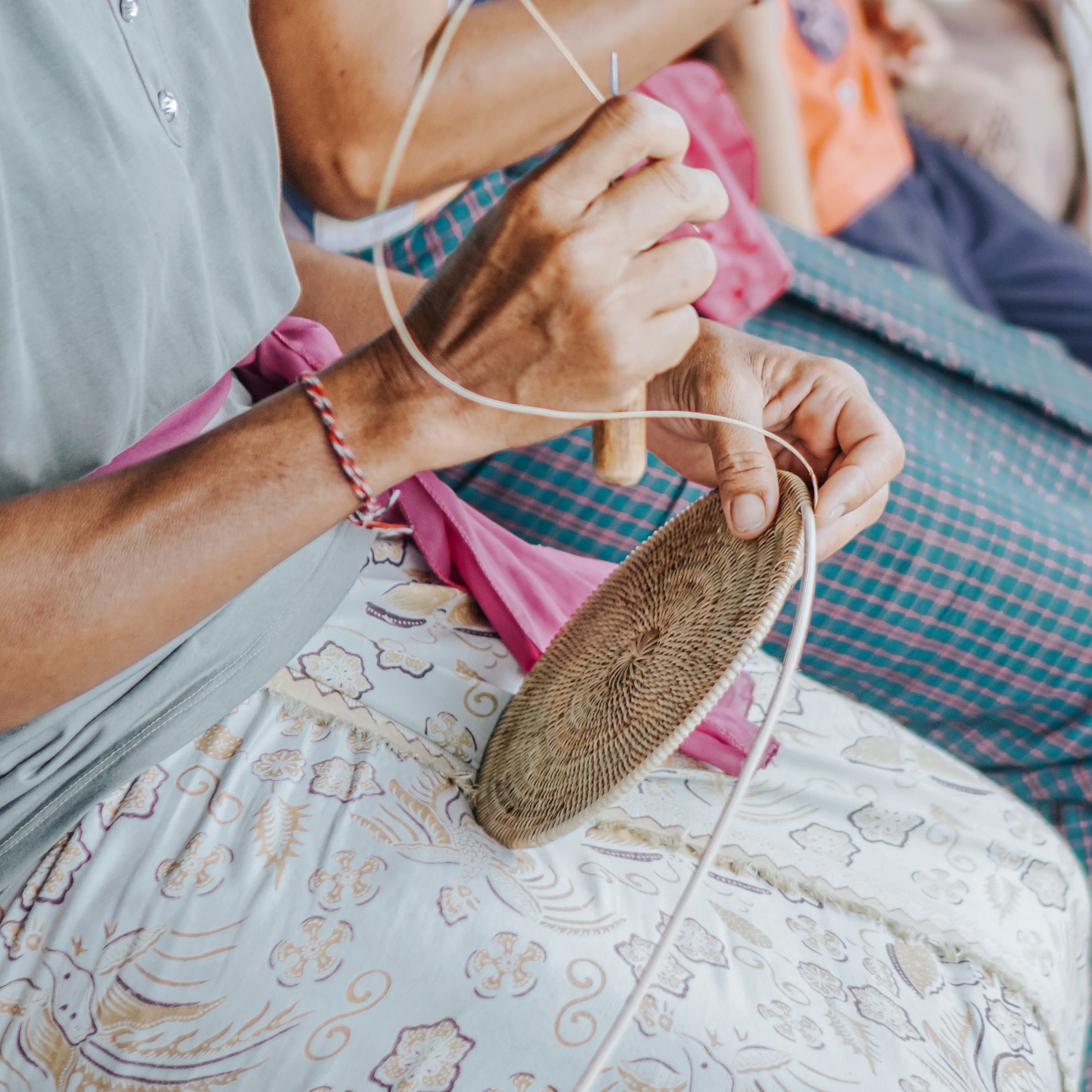 Person sitting while weaving rattan