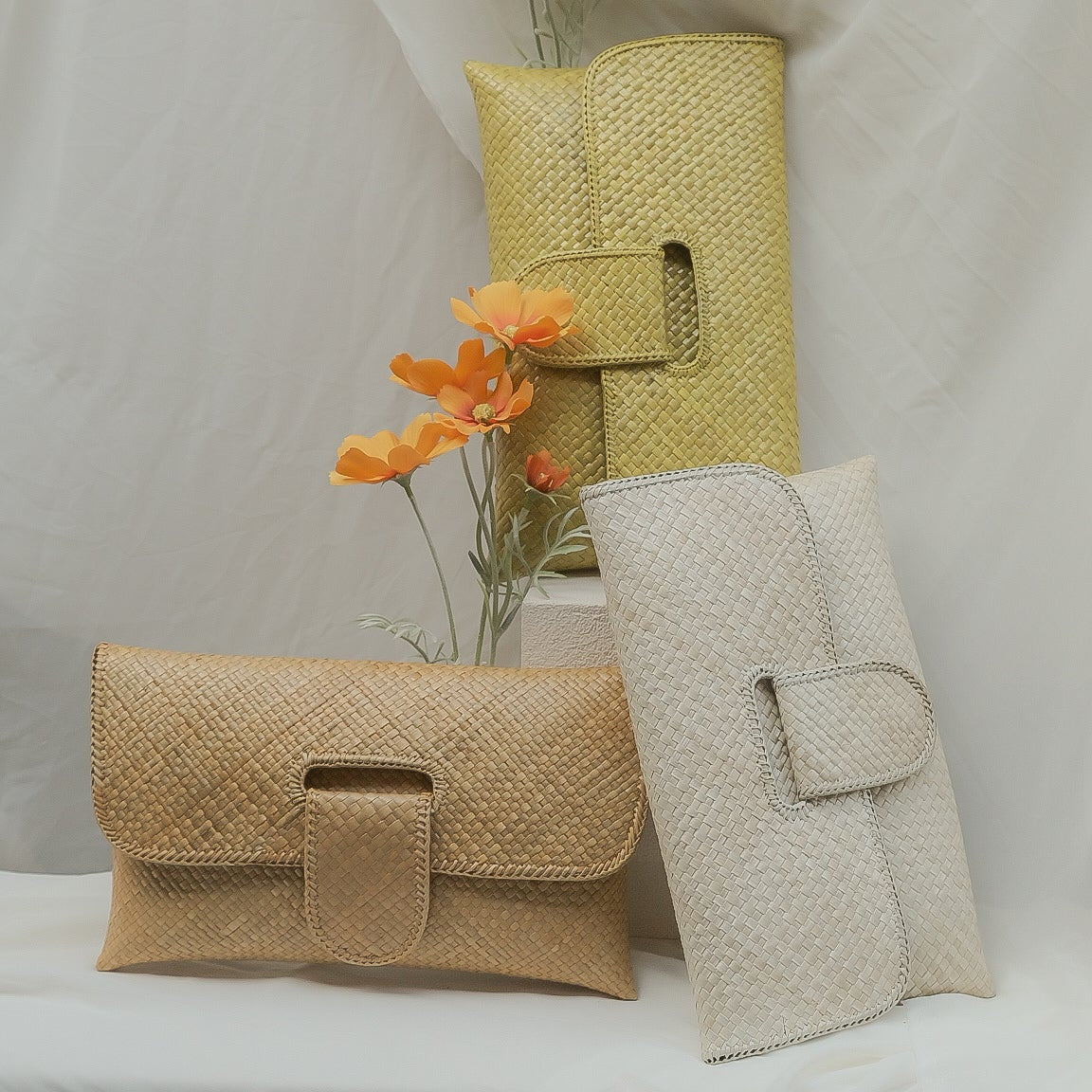 yellow, white and cream handbags on a white surface with draped fabric in the background