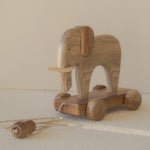 Wooden elephant toy with wheels on a neutral background