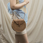 Woman holding a woven handbag against a neutral background