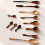 A set of ten wooden spoons in various sizes and shapes, arranged neatly on a light beige background with soft shadows.