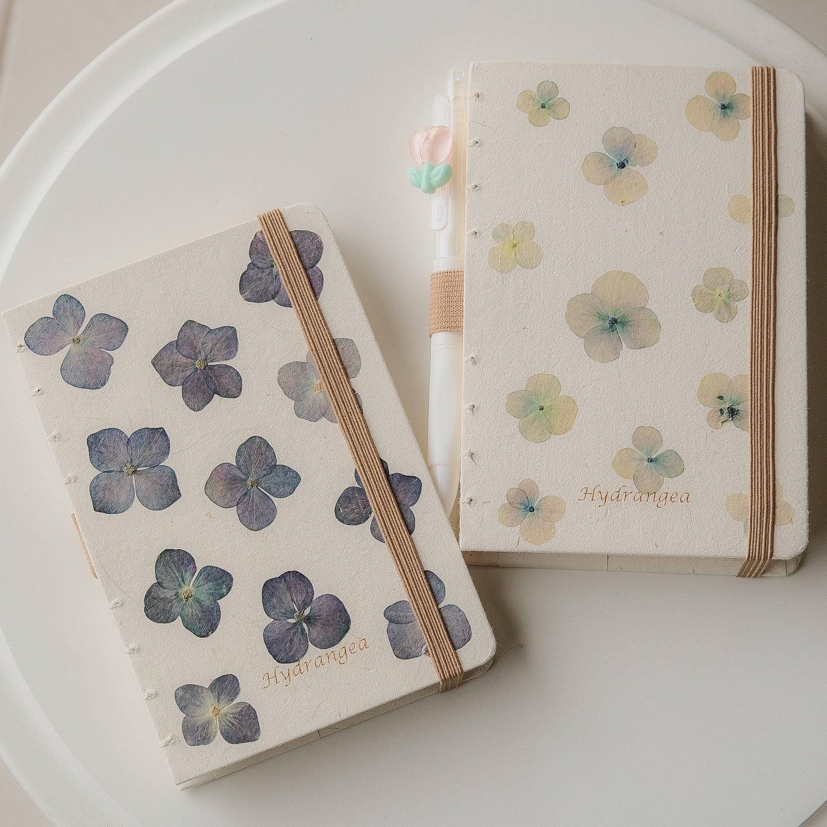 Two notebooks with floral designs on a white surface
