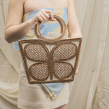 Person holding a woven handbag with a neutral background