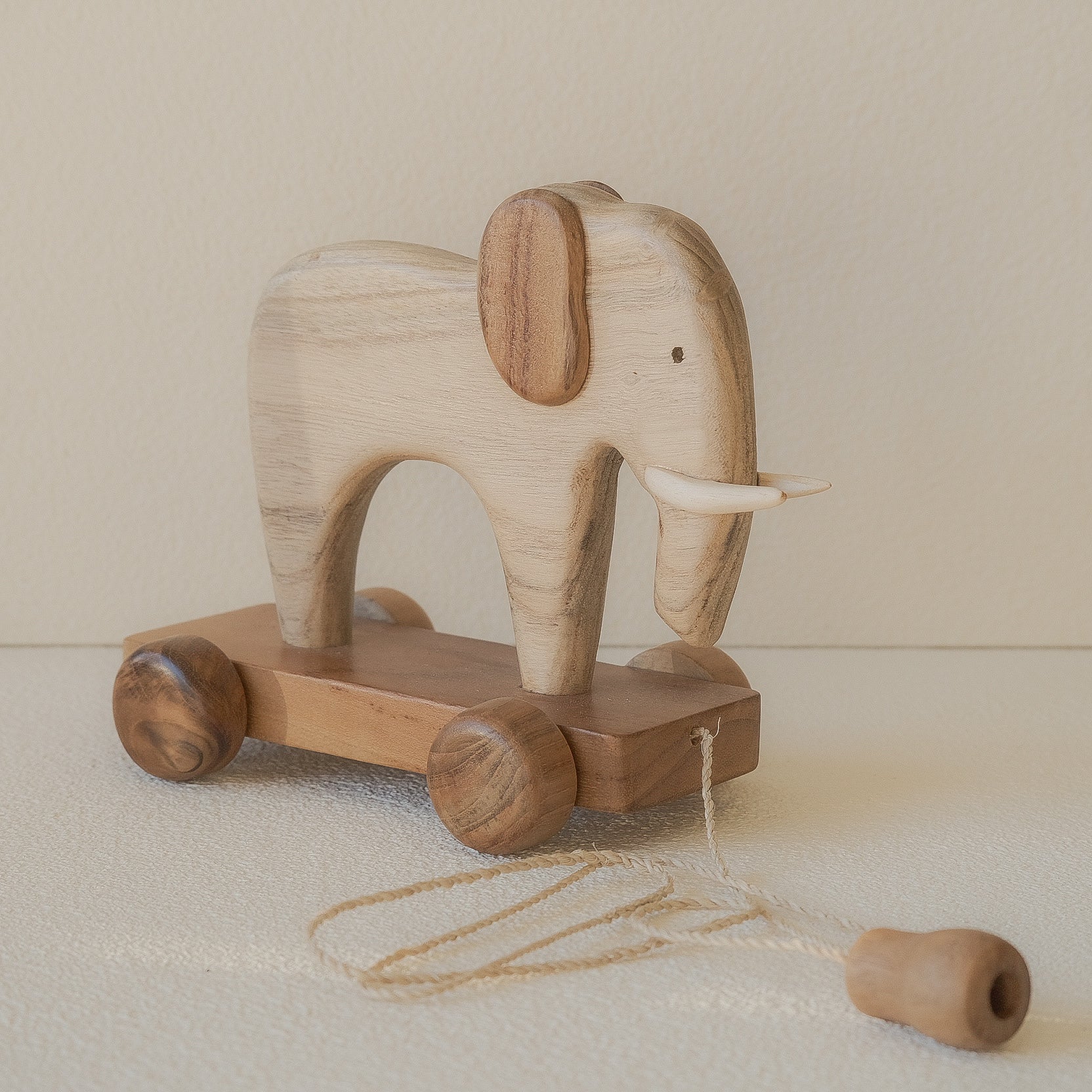 Wooden elephant toy with wheels on a beige background