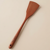 Wooden spatula with 'Kate & Co' branding on a beige background