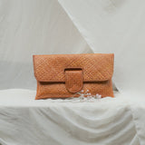 Orange woven clutch bag on a white draped surface