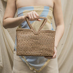 Person holding a woven basket against a neutral background