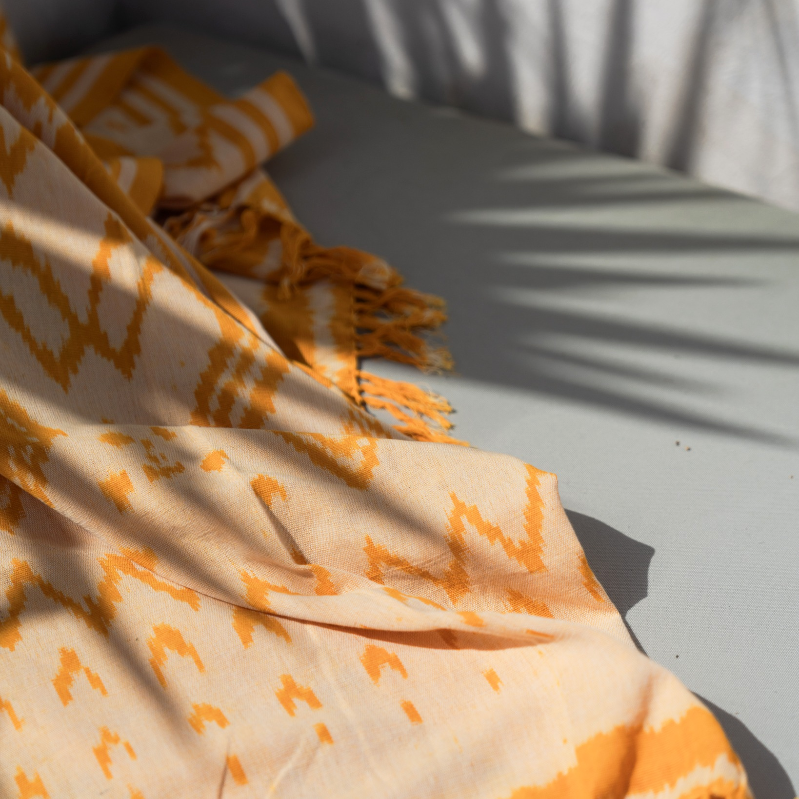 Orange and beige patterned blanket on a gray surface with shadows
