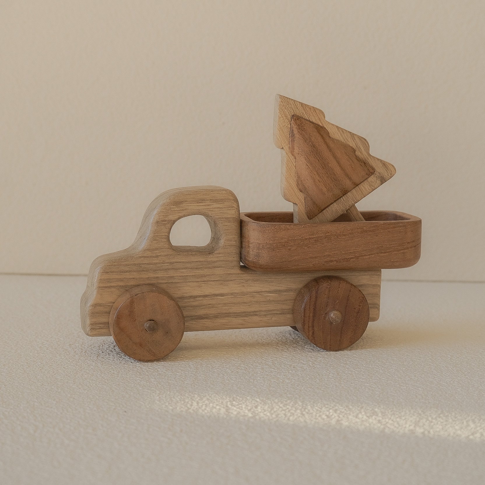 Wooden toy truck with a dump bed on a beige background