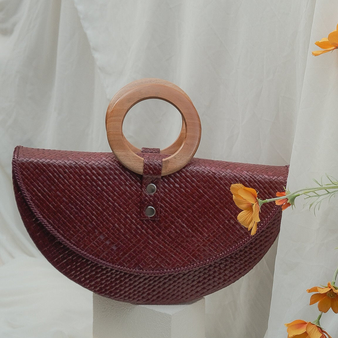 Woven handbag with wooden handle on a white background