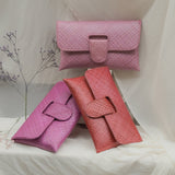 Three pink textured handbags on a white fabric background