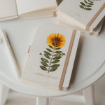 A6 recycled paper journal with real pressed calendula flower on the cover, paired with a floral pen and soft pouch