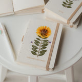 A6 recycled paper journal with real pressed calendula flower on the cover, paired with a floral pen and soft pouch