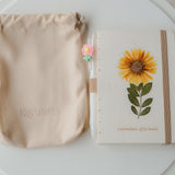 A6 recycled paper journal with real pressed calendula flower on the cover, paired with a floral pen and soft pouch