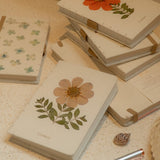 A6 cosmos flower journal with real pressed bloom on the cover, floral pen, and dust bag – colours may vary