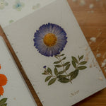Floral journal with pressed flowers on a wooden table surface
