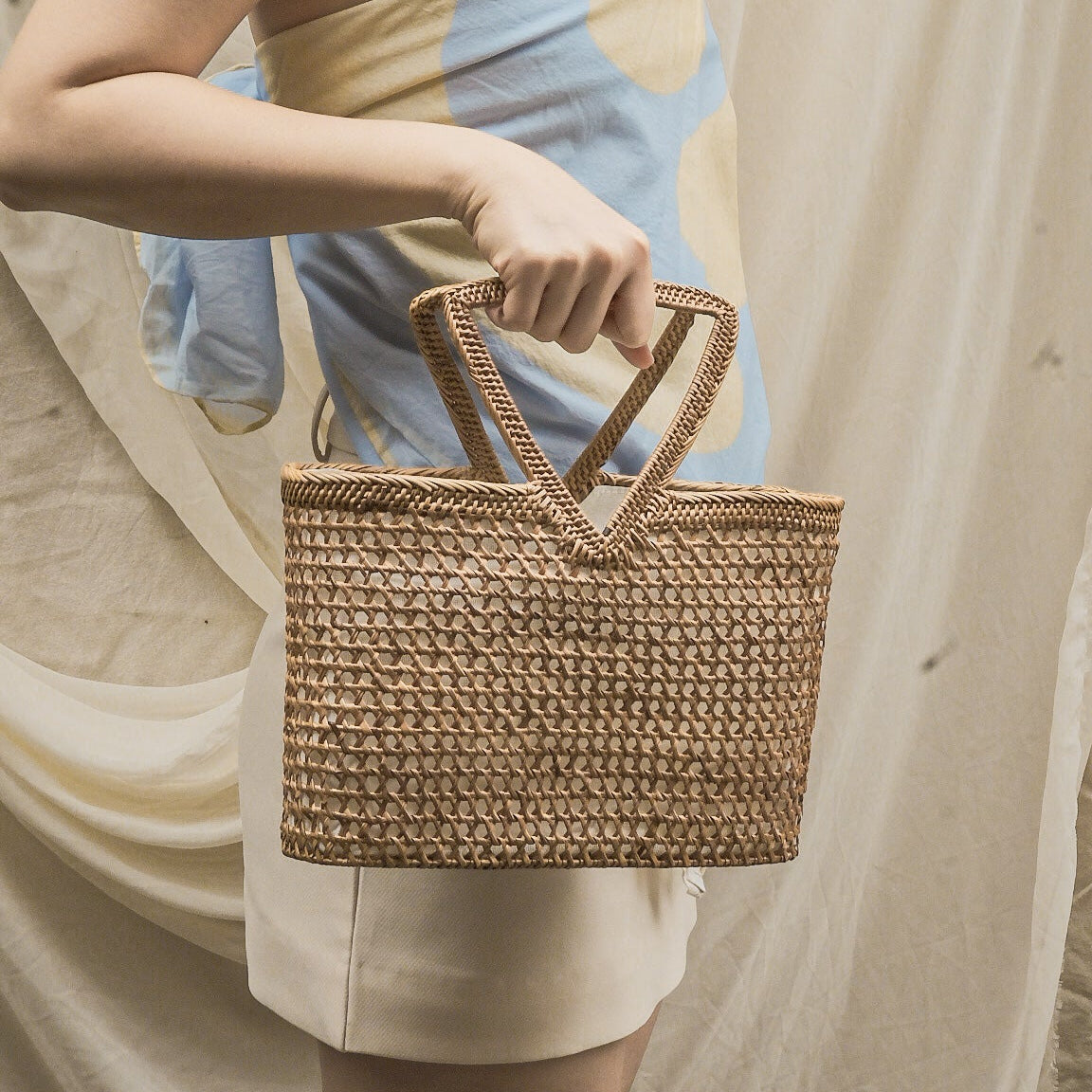 Person holding a woven basket with a neutral background