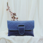 Blue woven clutch bag on a white fabric background