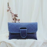 Blue woven clutch bag on a white fabric background