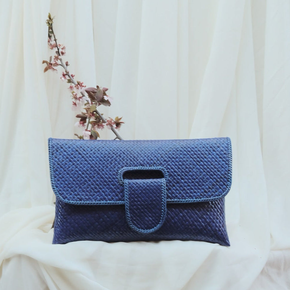 Blue woven clutch bag on a white fabric background