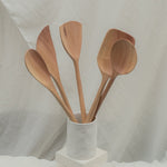 Set of wooden spoons in a white container on a light background