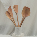 Set of wooden spoons in a white container on a light background