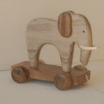 Wooden elephant toy on wheels with a plain background